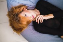 Red haired woman lying on bean bag and looking at camera — Stock Photo
