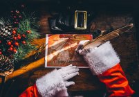 Above view of Santa Claus hands drawing with feather gift delivery routes on world map — Stock Photo