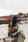 Rückansicht einer Frau mit Rucksack, die Kamera hält und Fotos macht — Stockfoto