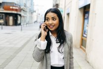 Элегантная деловая женщина с телефоном ходит по улице — стоковое фото