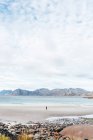 Вид на людину, що стоїть на піщаному узбережжі океану — стокове фото