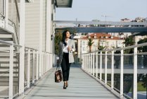 Vista frontale di elegante donna d'affari che trasporta borsetta e cammina al passaggio balcone — Foto stock