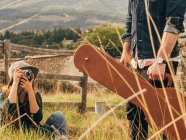 Woman taking shot of man with guitar case at countryside lawn — Stock Photo