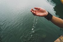 Cultiver main femelle prenant de l'eau du lac — Photo de stock