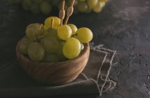 Vista de cerca del racimo de uvas verdes en la mesa oscura - foto de stock
