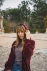 Morena chica en rojo sudadera con capucha posando en el parque - foto de stock