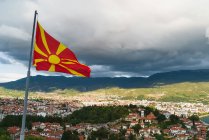 Размахивание флагом Македонии на фоне города, размещенного в горной долине . — стоковое фото