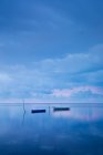 Boats floating in calm sea reflecting cloudscape — Stock Photo