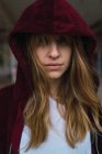 Retrato de menina morena com capuz vermelho casaco olhando para a câmera — Fotografia de Stock