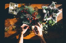 Draufsicht weiblicher Hände beim Basteln von Weihnachtsdekorationen auf sonnenbeschienenen Holztischen — Stockfoto