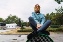 Стильная девушка сидит на вентиляции со скрещенными ногами — стоковое фото