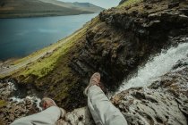 Guardando verso il basso vista di maschio seduto su scogliere bordo sopra torrente di montagna rapida — Foto stock