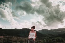 Mulher rindo posando no fundo da paisagem com montanhas sob nuvens . — Fotografia de Stock