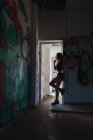 Vue latérale de la fille qui fume au trou de porte dans la chambre abandonnée — Photo de stock