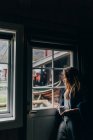 Donna in posa con tazza e guardando in finestra — Foto stock