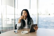 Retrato de mulher de negócios com tablet bebendo chá e olhando para o lado — Fotografia de Stock