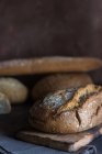 Nahsicht auf frische hausgemachte Brotlaibe auf rustikalem Brett — Stockfoto