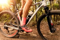 Crop male lg on bicycle pedal at pathway in forest — Stock Photo