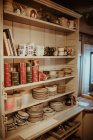 Wooden shelves with dinnerware at kitchen — Stock Photo