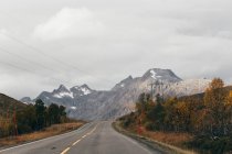 Vista panorâmica para picos altos e estrada de asfalto vazia nas montanhas . — Fotografia de Stock