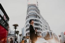 Seitenansicht einer Frau, die die Straße in der Innenstadt überquert — Stockfoto
