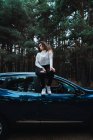 Portrait of brunette woman siting on top of car — Stock Photo