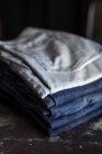 Pilha de calças jeans azuis na mesa escura . — Fotografia de Stock