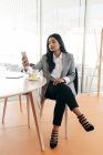 Портрет бізнес-леді, що переглядає смартфон, маючи чай — стокове фото