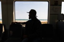 Silhouette einer Person im Zug, die am Zugfenster sitzt — Stockfoto