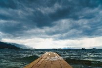 Perspektivischer Blick auf den leeren Holzsteg, der bei schlechtem Wetter in rauer See läuft. — Stockfoto