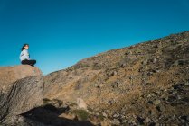 Frau sitzt auf Felsbrocken in trockener Berglandschaft — Stockfoto