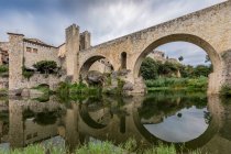 Vista del puente medieval sobre la superficie del río que refleja - foto de stock