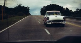 CUBA - AUGUST 27, 2016: White retro car driving on tropical  road — Stock Photo