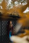 Brünettes Mädchen mit Kapuze lehnt romantisch an Zaun im Park — Stockfoto