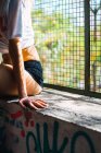Crop woman wearing black panties posing at window sill with grid — Stock Photo
