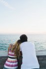 Вид сзади на пару, опирающуюся на парапет и любовающуюся морским пейзажем — стоковое фото