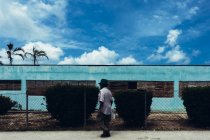 CUBA - 27 AOÛT 2016 : Vue de côté de l'homme marchant à côté d'un bâtiment industriel turquoise . — Photo de stock