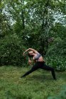 Seitenansicht des blonden Mädchens, das Yoga-Asana auf dem Rasen im Stadtpark durchführt — Stockfoto