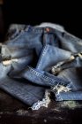 Fechar acima de calças de jeans azuis rasgadas na mesa escura . — Fotografia de Stock