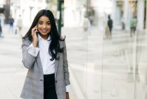 Smiling businesswoman talking phone and looking at camera — Stock Photo