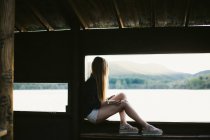 Unrecognizable woman sitting under bridge and admiring view of river. — Stock Photo