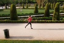 Вид збоку спортивна дівчина біжить на парковій алеї — стокове фото