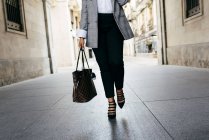 Baixa seção de fêmea com bolsa andando na rua — Fotografia de Stock