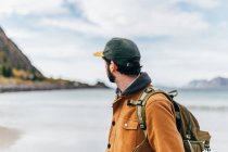 Vue latérale de l'homme touristique posant au lac dans les montagnes et regardant loin — Photo de stock