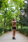 Athletic girl warming up shoulders before workout in summer park — Stock Photo