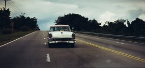 CUBA - AUGUST 27, 2016: View of white retro car driving on empty highway. — Stock Photo