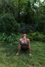 Vue de face de la femme en forme effectuant yoga asana dans le parc — Photo de stock