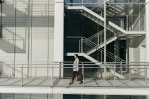 Seitenansicht einer eleganten Geschäftsfrau, die auf einem modernen Balkongang wandelt — Stockfoto
