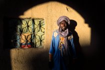 Marokko - 15. August: Schwarzer Mann in traditioneller Kleidung und Turban steht an der Wand und blickt in die Kamera. — Stockfoto