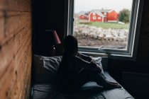 Silhouette de femme assise sur le lit et regardant par la fenêtre — Photo de stock